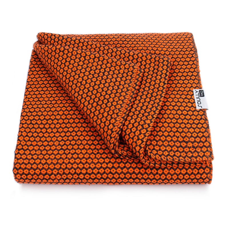 May include: Folded orange and black patterned blanket. The blanket has a repeating dot pattern and a tag that reads "SOULLY 150". The blanket is made of a soft, textured material.