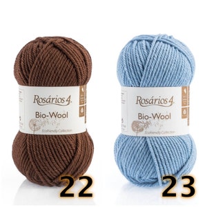 May include: Two skeins of Ros&aacute;rios 4 Bio-Wool yarn, one dark brown and one light blue. Each skein features a white paper label with the text Ros&aacute;rios 4 Bio-Wool Ecofriendly Collection and a dandelion graphic. The numbers 22 and 23 are visible.