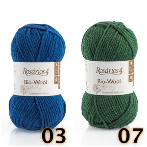 May include: Two skeins of Ros&aacute;rios 4 Bio-Wool yarn, one in deep blue and one in forest green. Each skein features a white paper label with the brand name, product name, and a dandelion graphic. The number 03 is below the blue yarn, and 07 is below the green.