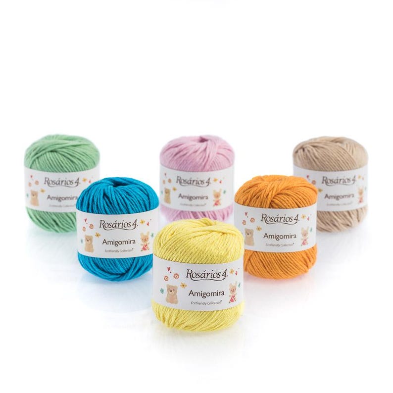 May include: Six balls of Ros&aacute;rios 4 Amigomira yarn in green, pink, beige, blue, yellow, and orange. Each ball features a white paper label with the brand name, the text Amigomira, and small illustrations of a bear and a rabbit on the front.