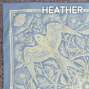 May include: A blue bandana with a white floral pattern and a bird design. The bandana has the word "HEATHER" printed in white at the top.
