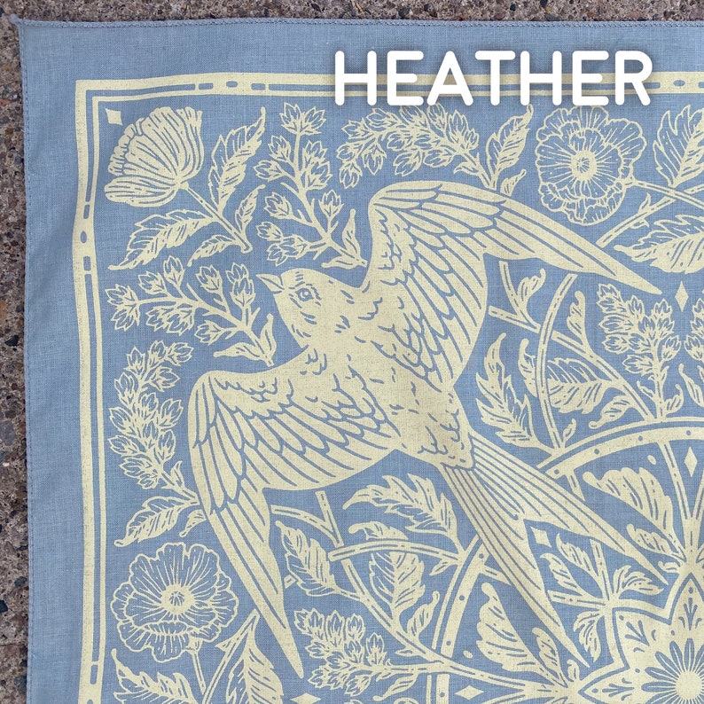 May include: A blue bandana with a white floral pattern and a bird design. The bandana has the word "HEATHER" printed in white at the top.
