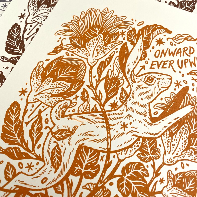 Pu&ograve; includere: Un'illustrazione marrone e bianca di un coniglio che corre attraverso un campo di fiori. Il coniglio &egrave; circondato da foglie e fiori. Il testo "ONWARD EVER UPWARD" &egrave; scritto in un font stilizzato sopra il coniglio.