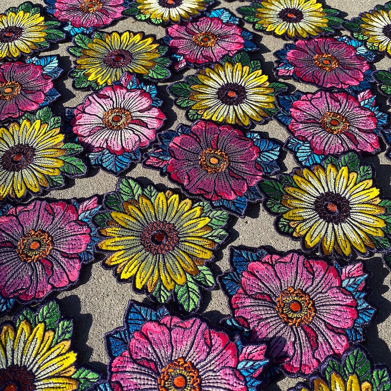 May include: A collection of colorful embroidered flower patches. The patches feature a variety of flowers, including sunflowers, daisies, and roses. The patches are perfect for adding a touch of whimsy to clothing, bags, or other accessories.