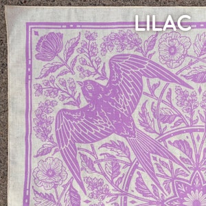 May include: Lilac bandana with a white background and a purple floral pattern. The pattern includes a bird, flowers, and leaves. The word "Lilac" is printed in the top right corner.