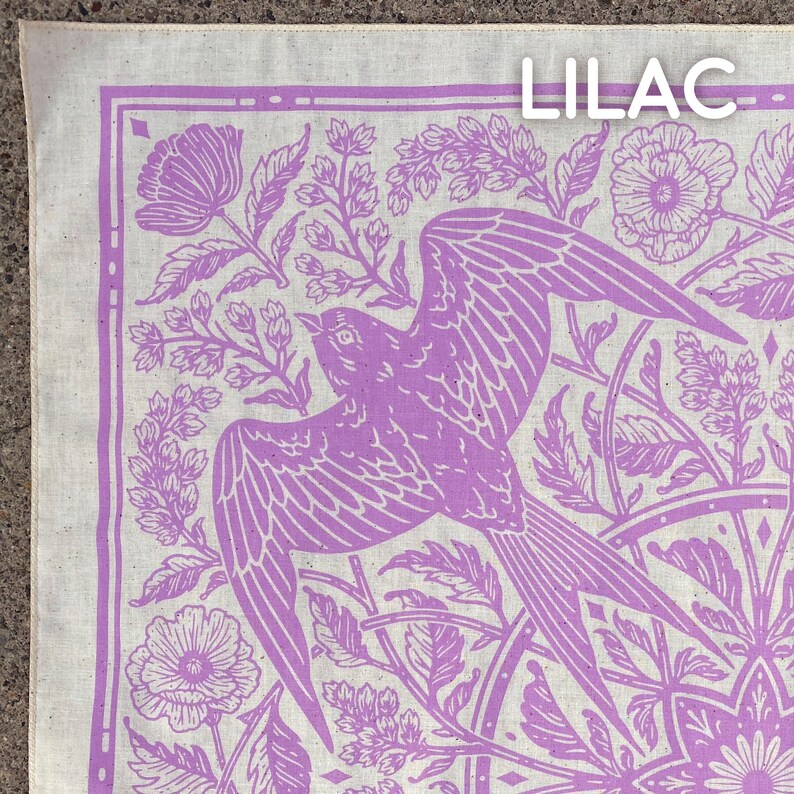 May include: Lilac bandana with a white background and a purple floral pattern. The pattern includes a bird, flowers, and leaves. The word "Lilac" is printed in the top right corner.