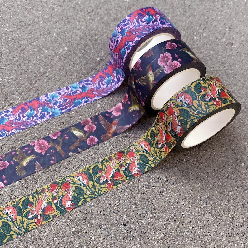 May include: Four rolls of decorative washi tape with different floral and animal designs. The tape is colourful and features hummingbirds, mice, and flowers.