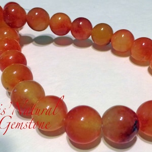May include: A strand of orange and yellow gemstone beads. The beads are round and have a smooth, polished finish.