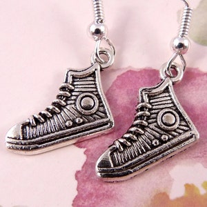 May include: A pair of silver tone earrings featuring a detailed design of a high-top trainer.