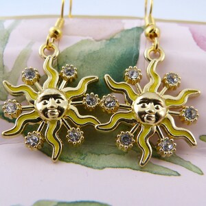 May include: A pair of gold-tone earrings featuring a yellow enamel sun design with clear rhinestones.