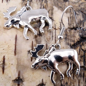 May include: A pair of silver moose earrings with a dangling design. The moose are facing to the left and have detailed features.