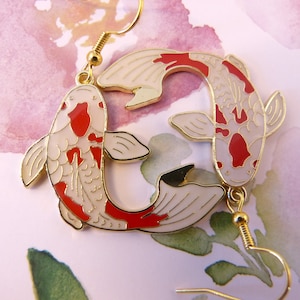 May include: Gold tone earrings featuring a pair of red and white koi fish, a traditional Japanese symbol of good luck and prosperity.
