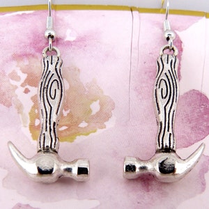 May include: A pair of silver hammer earrings with a wood grain design on the handle.