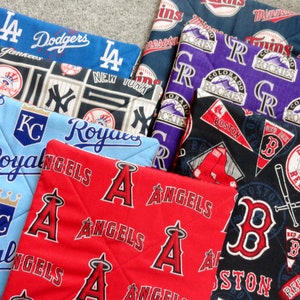May include: A collection of eight fabric squares featuring different Major League Baseball team logos. The logos include the Los Angeles Dodgers, New York Yankees, Kansas City Royals, Los Angeles Angels, Colorado Rockies, Boston Red Sox, and Minnesota Twins.
