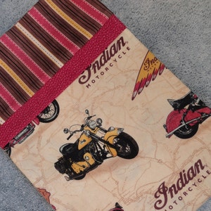 May include: A beige fabric pouch with a pink leather trim and brown and red striped fabric. The pouch features the text "Indian Motorcycle" and an illustration of a motorcycle.