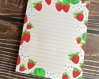 May include: A white pen with a yellow bee design on the top, a roll of clear tape, and a notepad with a strawberry border. The notepad has lined paper.