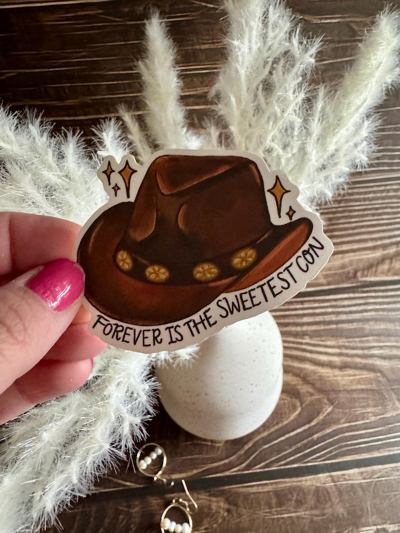 May include: A brown cowboy hat with a floral band and the text "Forever is the Sweetest Con" on a white background.
