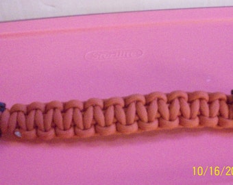 May include: Orange paracord bracelet with a black plastic buckle. The bracelet is made of tightly woven orange cord and features a secure clasp. The date "10/16/2014" is visible in the bottom right corner.