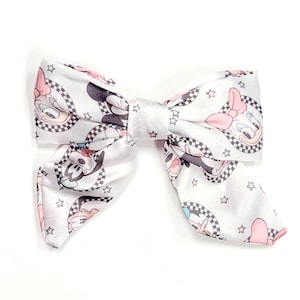 May include: White satin bow with a checkered and star pattern featuring cartoon images of Mickey Mouse and Minnie Mouse.