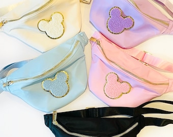 May include: Five fanny packs in different colors with a fuzzy Mickey Mouse head patch on each. The colors are white, lavender, light blue, pink, and black.