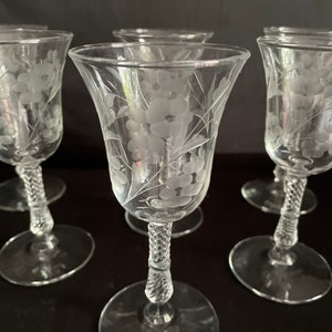 May include: Set of clear glass wine glasses with etched floral designs. Each glass features a flared bowl, a twisted stem, and a round base. The floral pattern is delicately etched onto the glass, adding a touch of elegance.