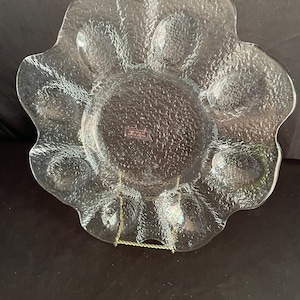 May include: A clear glass serving dish with a scalloped edge and six individual indentations. The dish has a textured surface and is made by the brand "Hand Made in Czechoslovakia".
