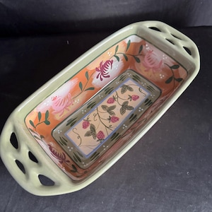 May include: Rectangular ceramic serving dish with a light green rim and handles. The interior features a floral design with pink roses and a central strawberry motif. The dish is painted with orange, green, and pink accents.