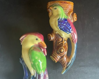 May include: Two ceramic bird wall planters with a brown tree branch design. The birds are painted in shades of yellow, green, blue, and red.