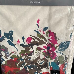 May include: A white cotton tablecloth with a floral pattern in shades of pink, red, green, and blue. The tablecloth is 60 inches by 104 inches. The text "AMAN" is printed on the packaging, along with the words "New charm, New Feel, New Life" and "TABLE CLOTH".