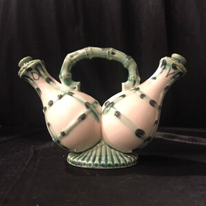 May include: A ceramic oil and vinegar cruet with a bamboo-style handle. The cruet is white with a green and black dot pattern. The base and handle are green.