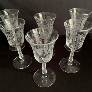 May include: Six clear glass cordial glasses with etched floral designs. Each glass features a flared bowl, a twisted stem, and a round base. The etched floral pattern is visible on the bowl of each glass.