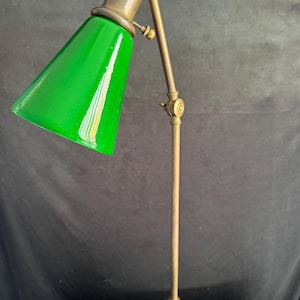 May include: A vintage brass desk lamp with a green glass shade. The lamp has a flexible arm and a round base.