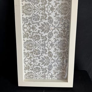 May include: White picture frame with a decorative silver and white patterned background.