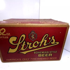 May include: A vintage Stroh's Bohemian Style Beer box. The box is red with gold lettering and a crest. It reads "32 oz. Bottles" and "America's Only Fire-Brewed Beer."