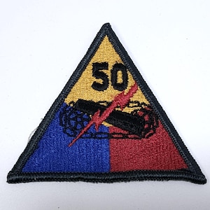 May include: Embroidered patch in a triangular shape. The top section is gold with the number 50 in black. The bottom is split into blue and red sections, with a black tank and red lightning bolt.