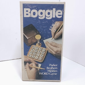 May include: A vintage Boggle game box with a blue background and the word "Boggle" in white. The box features illustrations of hands, a notepad, a timer, and the Boggle game board. The text "Parker Brothers Hidden WORD Game" is also visible.