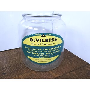 May include: A vintage glass jar with a yellow and green label that reads "Devilbiss No. 145 Vaporizer". The label also states "8-10 Hour Operation with Normal Water and Current Automatic Shut-Off 110-120 Volts A.C. Only 5 Amperes Follow Instructions Keep Unit Clean".