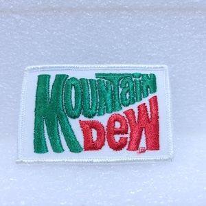 May include: White embroidered patch with the words "Mountain Dew" in green and red lettering.