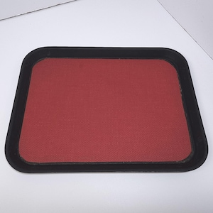 May include: A rectangular tray with a textured, brick-red surface and a black border. The tray has rounded corners and a simple, functional design. The background is white.