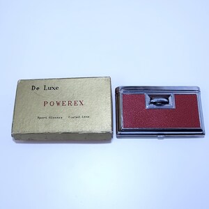 May include: Vintage Powerex De Luxe sport glasses binoculars with a red textured finish and silver trim. The box is gold with the text "De Luxe" and "Powerex". The box also says "Sport Glasses Coated Lens".
