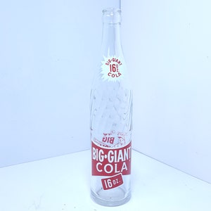 May include: Clear glass Big-Giant Cola bottle with red lettering and a white starburst graphic. The bottle has a textured design and a label that reads "16 oz."