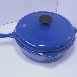 May include: A blue cast iron skillet with a lid. The skillet has a long handle and a lid with a black knob. The cookware is a vibrant blue color and appears to be new.