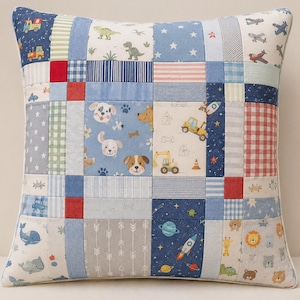 May include: A square throw pillow featuring a patchwork design with various printed fabric squares. Patterns include blue and white stars, red and white gingham, stripes, and illustrations of dogs, dinosaurs, construction vehicles, space rockets, and whales.