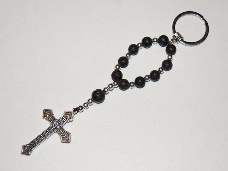 May include: A black lava rock beaded keychain with a silver cross charm and a silver key ring.