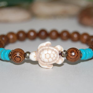 May include: A brown wooden beaded bracelet with a white turtle charm and turquoise beads.