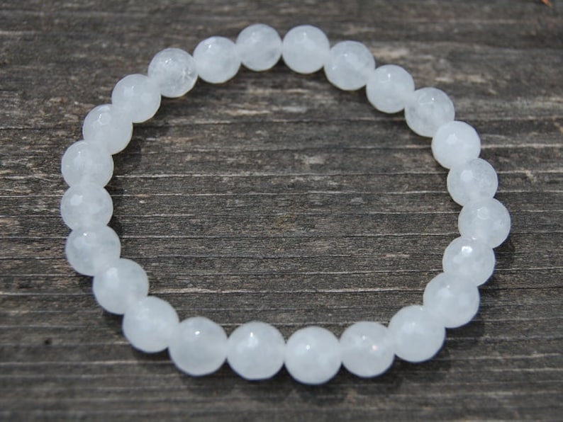 May include: White gemstone bracelet with round beads. The bracelet is made of white beads with a frosted finish.