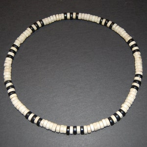 May include: A black and white wooden beaded necklace. The beads are round and have a black stripe around the middle.
