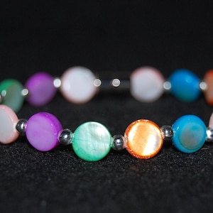 Op de afbeelding: Een kleurrijke armband gemaakt van ronde, iriserende kralen. De kralen zijn in tinten paars, wit, groen, oranje en blauw.