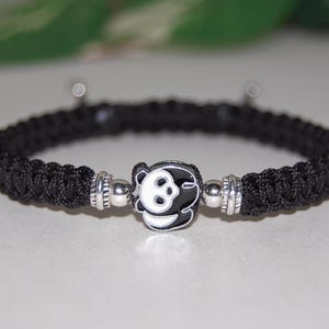 Puede incluir: Pulsera de paracord negro con un dije de plata con dise&ntilde;o de panda.