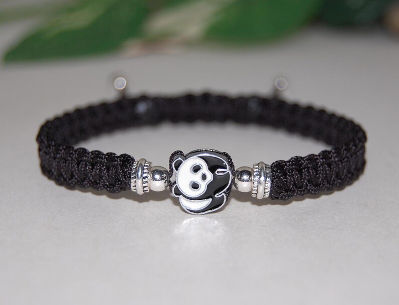 Puede incluir: Pulsera de paracord negro con un dije de plata con dise&ntilde;o de panda.